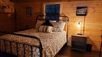 Une pièce de style cabane en bois, avec un lit, une table de chevet, une lampe et un panneau accroché au mur.