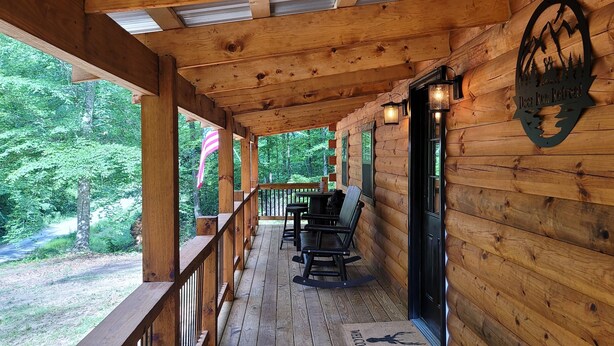 A wooden cabin with a porch, outdoor seating, and a sign indicating a deer hunt retreat. - Secluded East TN Log Cabin (Ten Mile)