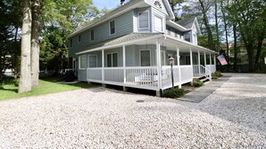 A two-story house with a porch, a front yard, and a gravel driveway. - ONLY A 7 MINUTE WALK TO THE BEACH! (Bethany Beach)