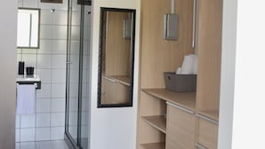 Ein modernes Badezimmer mit Glasdusche, einem Holzkosmetikschrank und einem großen Spiegel.