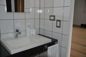 A bathroom with a white sink, black countertop, and tiled walls.