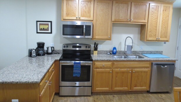 A kitchen with wooden cabinets, a stainless steel microwave, oven, and dishwasher.