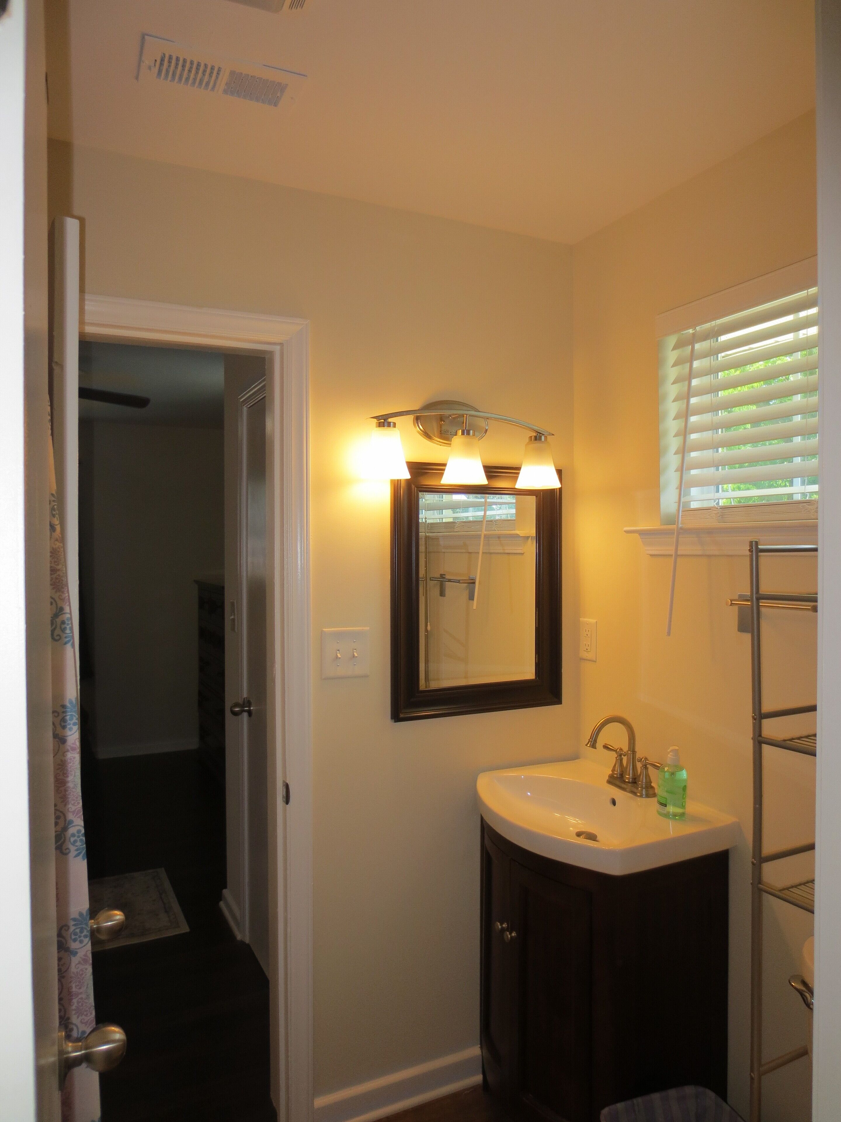 A bathroom with a sink, mirror, and towel rack.