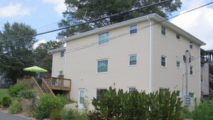 A multi-story building with a beige exterior, a visible number '219' on the side, and a small deck with a green umbrella.
