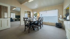 A dining area with a table and chairs, a view of the water, and a kitchen area with a stove and sink.