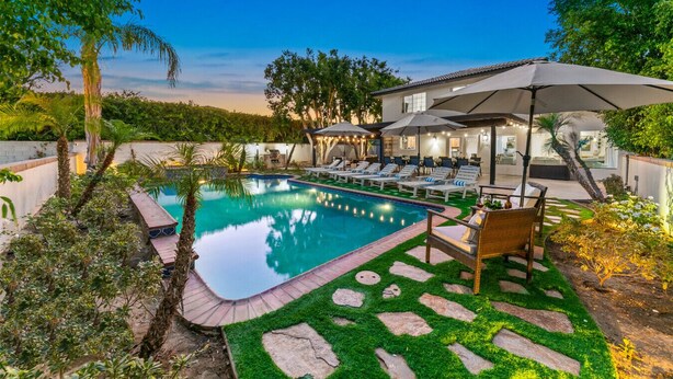 A swimming pool with lounge chairs, a covered seating area, and a stone pathway. - Large Home 12 beds Gameroom Heated Salt Pool PPG (Palm Desert)
