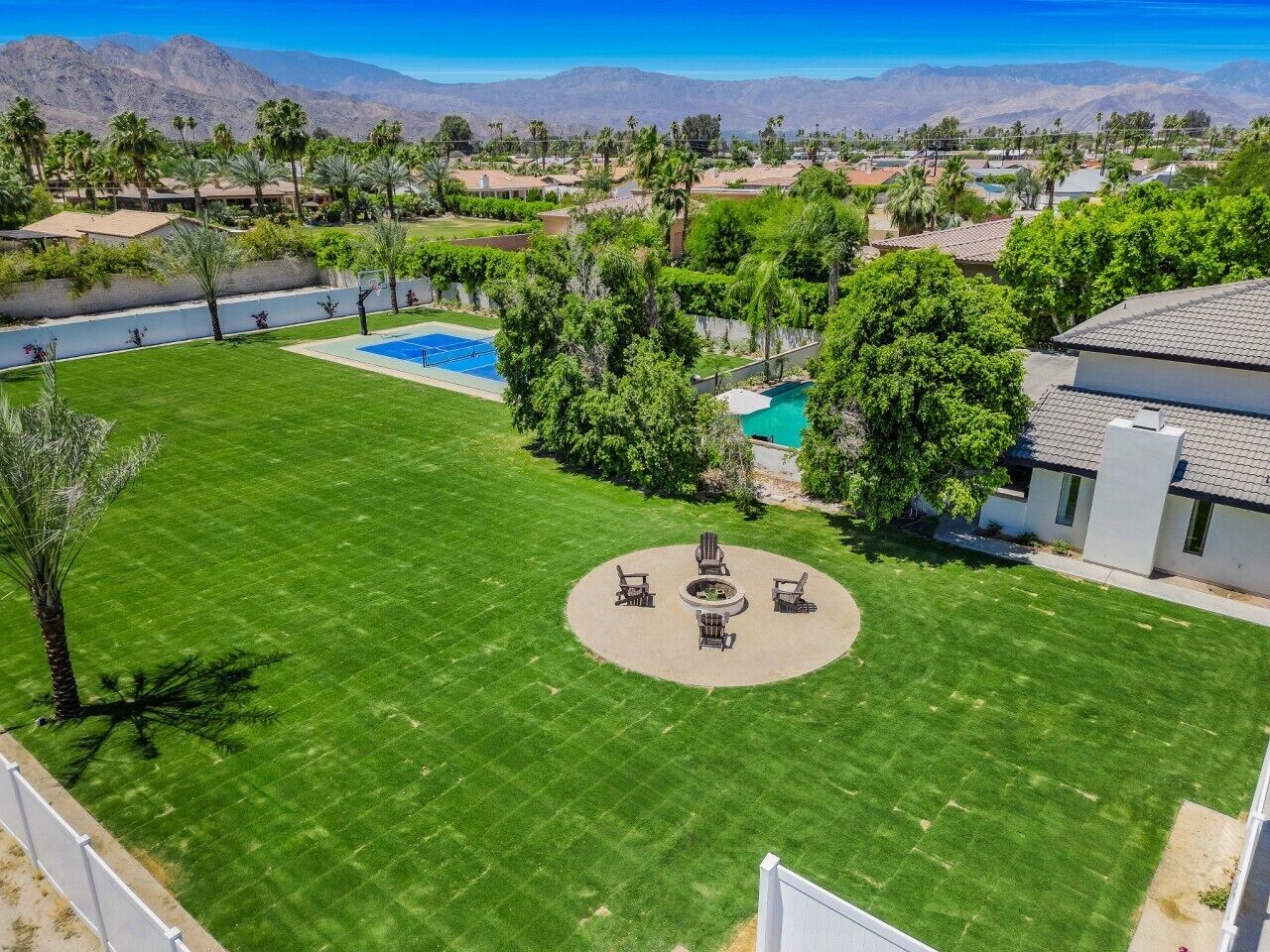 A backyard with a circular seating area, a swimming pool, and a view of mountains.
