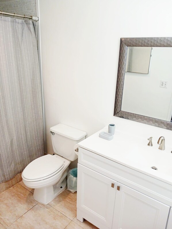 A bathroom with a toilet, a sink with a mirror, and a shower curtain.
