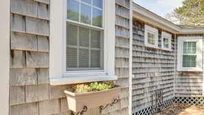 A house with a window with a planter box attached to the exterior wall.