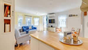 A bright kitchen with a wooden countertop, a blue sofa, and a striped armchair.