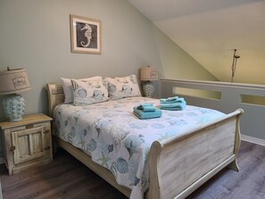 A bedroom with a bed, two nightstands, a lamp, a framed picture on the wall, and a wooden chest of drawers.