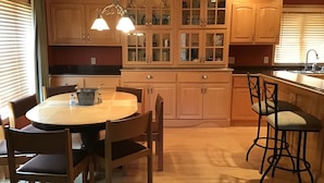 A kitchen with wooden cabinets, a dining table with chairs, and a bar area. - Enjoy Northern MN (Cook)