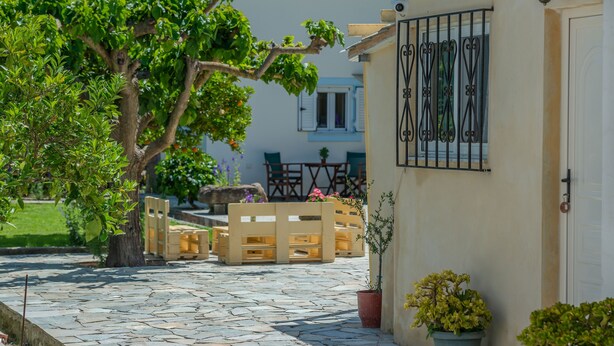 A courtyard with a stone floor, wooden benches, and potted plants. - Kipi Village Zakynthos (Ζάκυνθος)