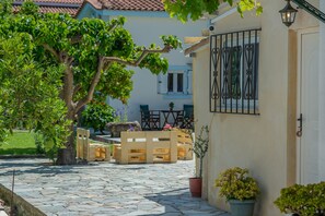 Une cour avec un sol en pierre, des bancs en bois et des plantes en pot.
