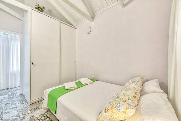Une chambre à coucher avec un lit, une armoire et une fenêtre avec des rideaux.