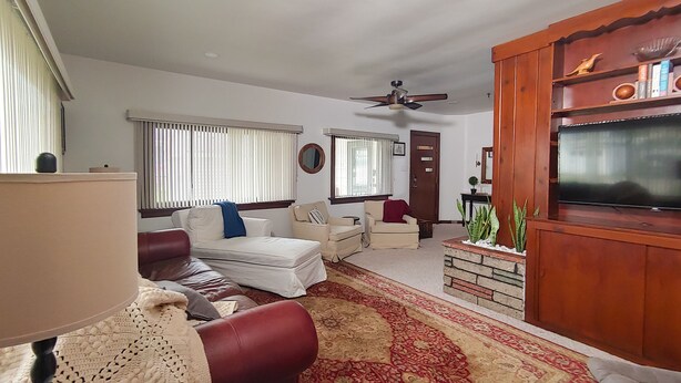 A living room with a sofa, armchairs, a coffee table, a TV, and a ceiling fan. - Huge historic on Lake Michigan w/ large yard, fire pit, BBQ & air conditioning (Manistee)