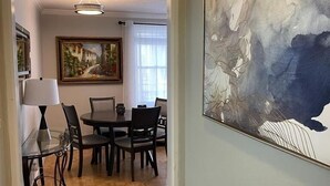 A dining area with a table and chairs, a painting on the wall, and a hallway leading to another room. - Cozy place in heart of Atlanta  (Atlanta)