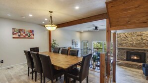 Un coin repas avec une table et des chaises en bois, un ventilateur de plafond et une cheminée en pierre.