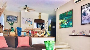 A living room with a sofa, a coffee table with decorative items, a ceiling fan, and a painting on the wall.