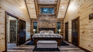 Ein Schlafzimmer in einer Blockhütte mit einem großen Bett, zwei Nachttischen und einem Fenster.