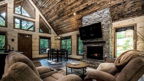 Ein gemütliches Blockhaus-Interieur mit Kamin aus Stein, Holzwänden und Essbereich.