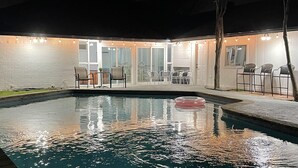 A swimming pool with a floating ring, surrounded by a covered patio area with chairs and tables. - Family friendly/POOL/Sleeps 16/Luxury (Plano)