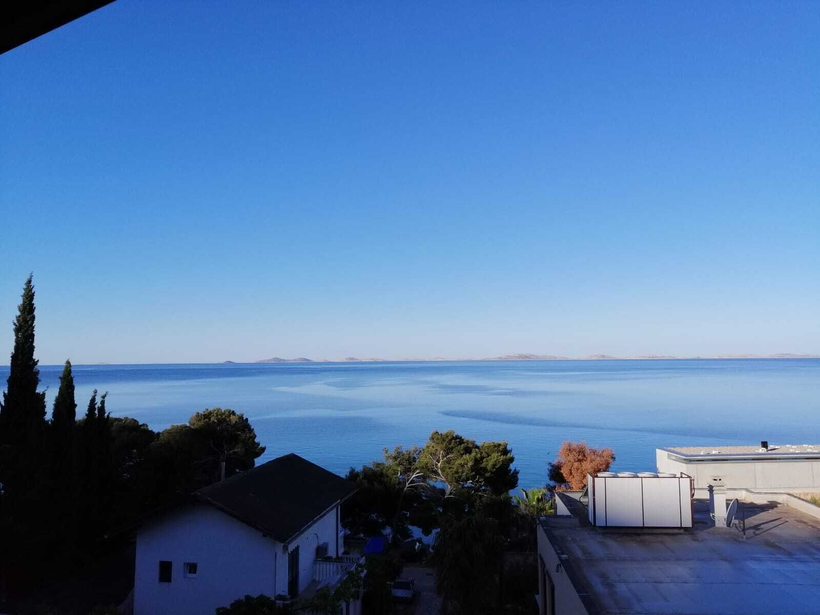 A residential area with a view of a calm sea and distant landforms.