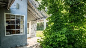 Ein gepflasterter Weg führt zu einem Haus mit einer Veranda und einem großen Busch.