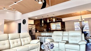 A modern living room with leather sofas, a dining area, and a kitchen with a stone backsplash. - LOCATION - DUNWOODY; NEW-BEAUTIFUL MODERN HOUSE & Outdoor Seasonal Private Pool (Atlanta)