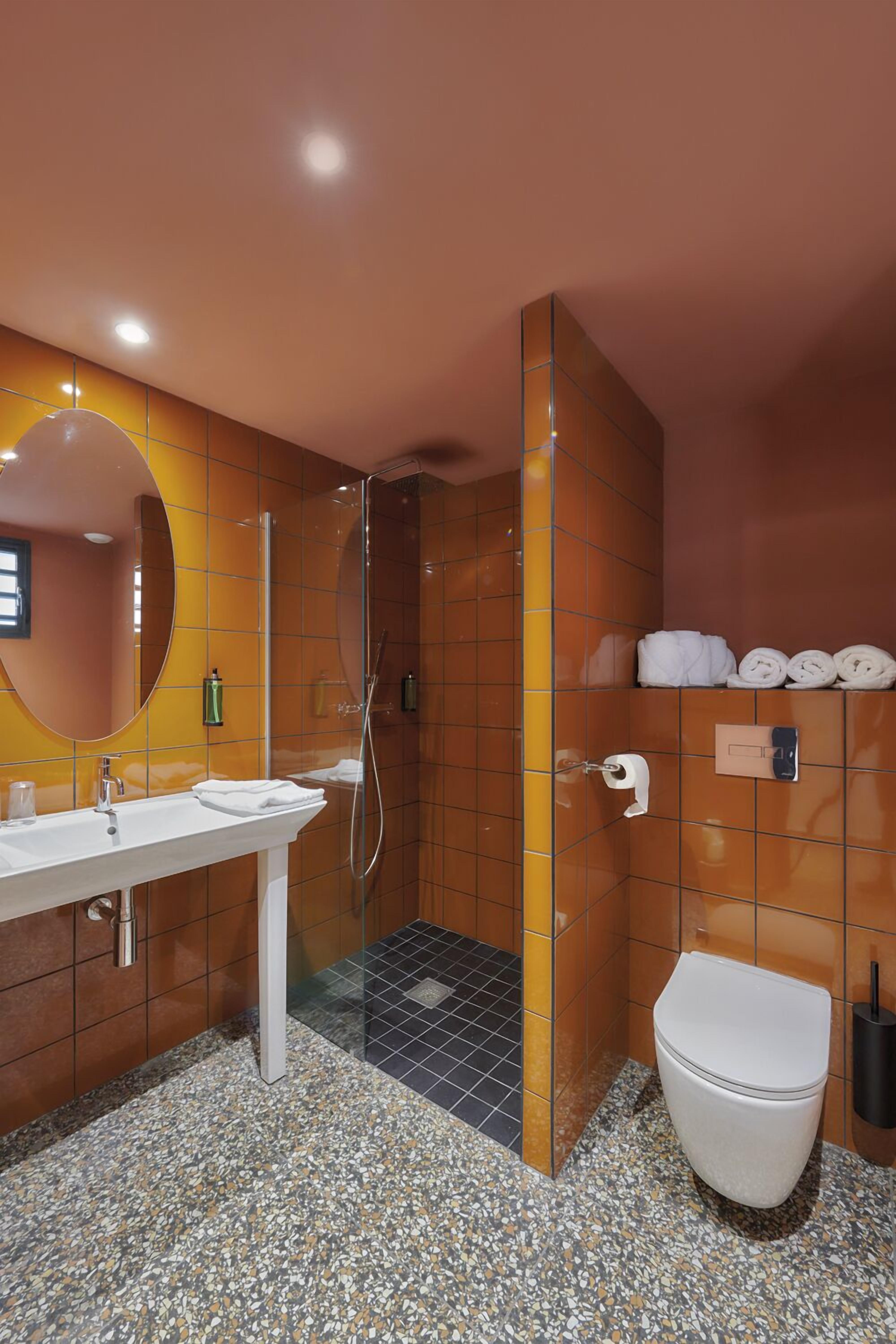 Een moderne badkamer met een wit wastafel, een spiegel, een douche en een toilet.