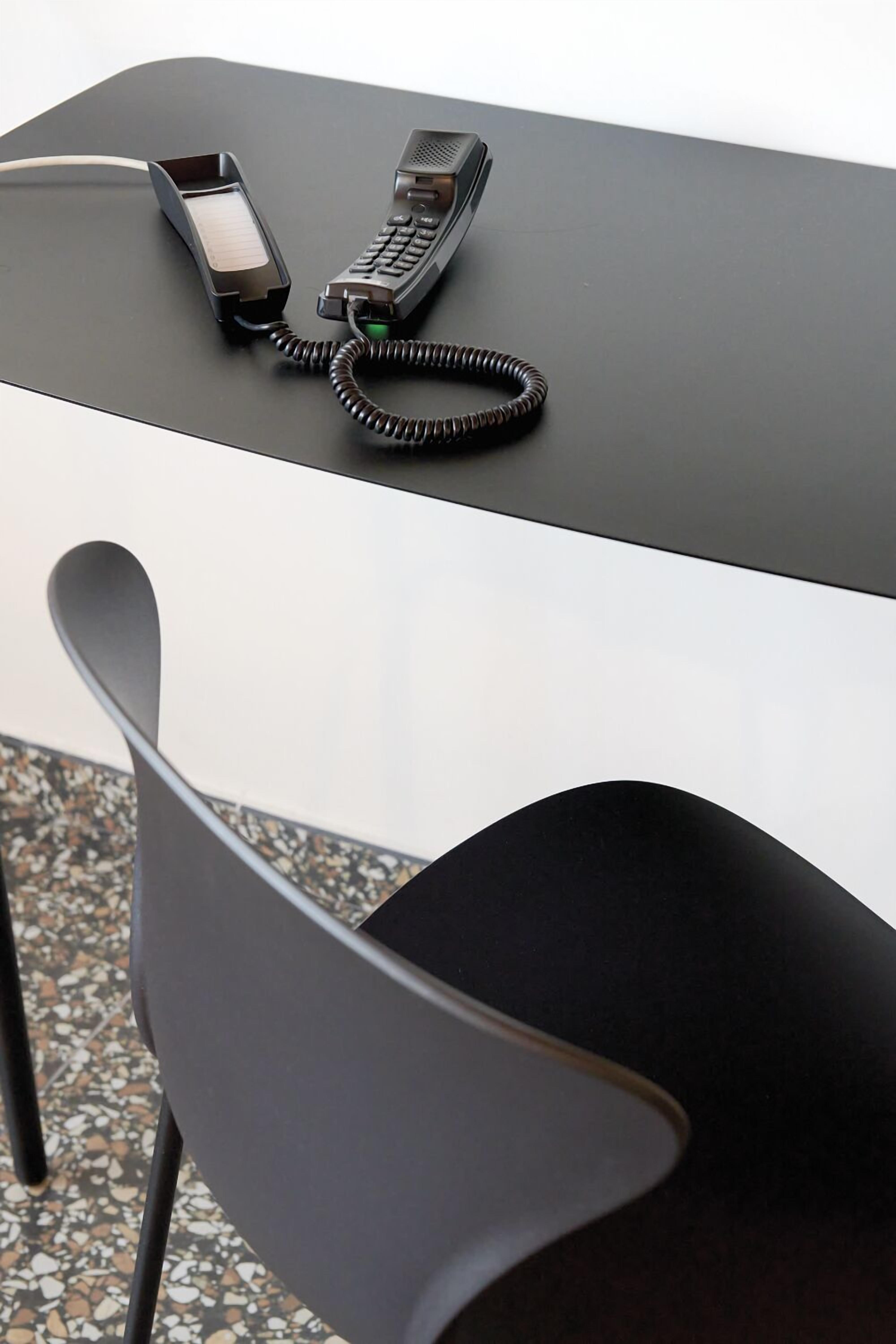 Ein moderner Schreibtisch mit Telefon und aufgewickeltem Kabel.
