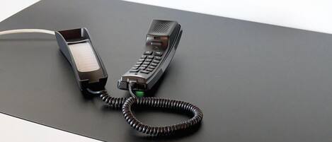 Ein moderner Schreibtisch mit Telefon und aufgewickeltem Kabel.