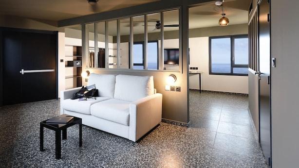 Een moderne woonkamer met een witte bank, een bijzettafeltje en een grote spiegel.