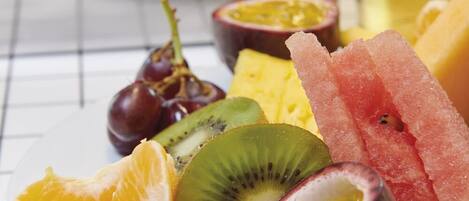 A plate of assorted fruits including kiwi, passion fruit, and watermelon, with a glass of iced tea in the background.