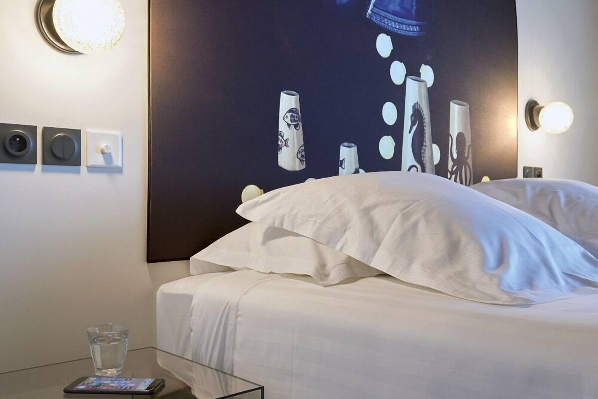 Een hotelkamer met een bed, een glazen tafeltje en een muur met een groot poster.