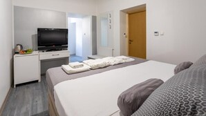 A hotel room with a bed, a TV, a desk, and a wardrobe.