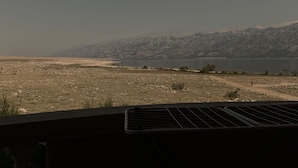 A view from a window overlooking a barren landscape with distant mountains and a body of water. - Villa ata Razanac - Apartment With sea View (Razanac)