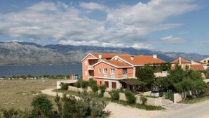 A coastal property with a large building, a view of the sea, and mountains in the background. - Villa ata Razanac - Apartment With sea View (Razanac)