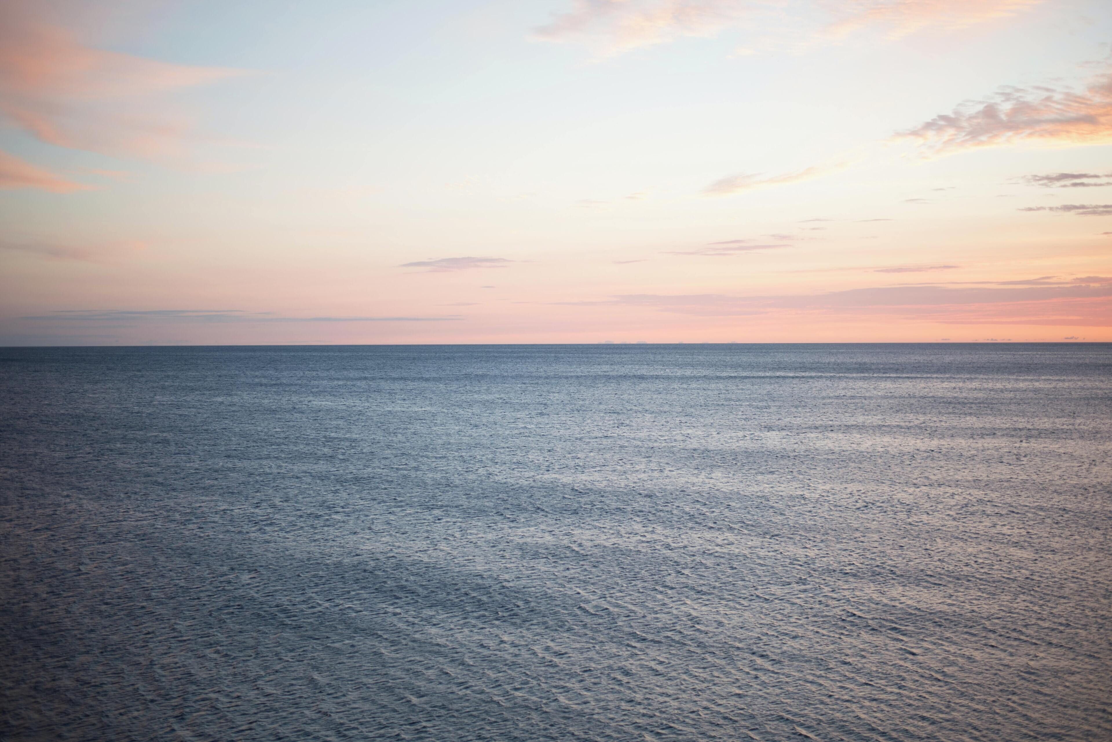 A calm sea at sunset with a clear horizon.