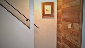 Eine Treppe mit hölzernem Geländer, ein gerahmtes Bild an der Wand und eine Wandverkleidung aus Holz.