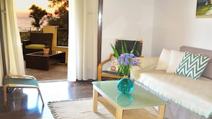 A living room with a sofa, chairs, a coffee table, and a vase with flowers. - Holiday House Angelos C on Agios Gordios Beach (Corfu)