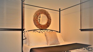 A four-poster bed with a woven headboard, two pillows, and a patterned bedspread. - Arhaus 3 Serene Two-bedroom Retreat (Grand Forks)