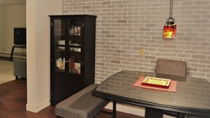 A dining area with a glass table, bench, and a black cabinet with glass doors. - Arhaus 3 Serene Two-bedroom Retreat (Grand Forks)