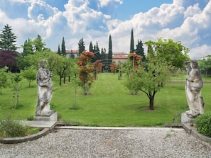 A garden with statues, a lawn, and a building in the background.