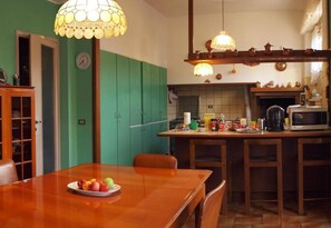 A kitchen with a wooden table, green cabinets, and a microwave.