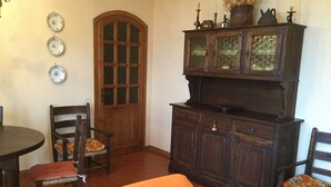 Ein Essbereich mit einem Holztisch, zwei Stühlen, einer Vitrine und einer Tür mit Fenster.