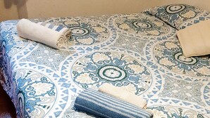 Ein Bett mit einem gemusterten Überwurf und zwei aufgerollten Handtüchern.