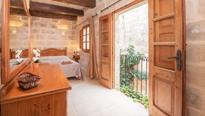 A bedroom with a wooden bed, a bedside table, a mirror, and a view of a courtyard. - 3 Bedrooms House of Character in Rabat Near Mdina - Casa Melita (Rabat)
