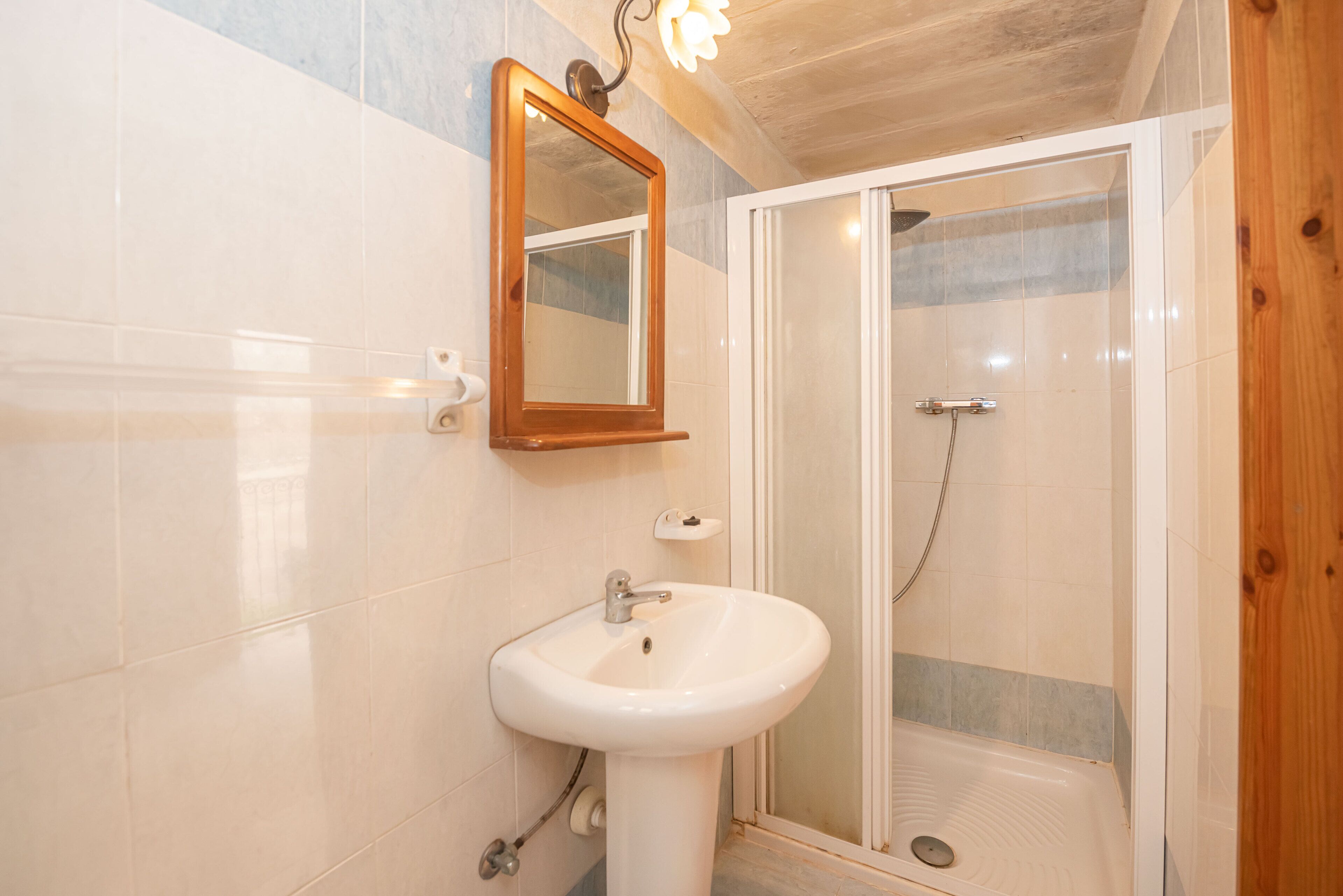 A bathroom with a white sink, a mirror, and a glass-enclosed shower.