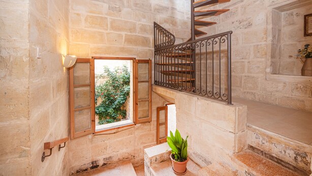 A stone staircase with a wooden handrail, a potted plant, and a window with a view of greenery. - 3 Bedrooms House of Character in Rabat Near Mdina - Casa Melita (Rabat)